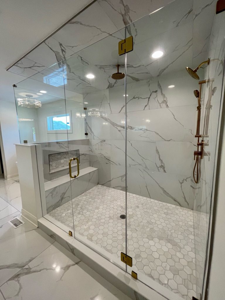 Walk-in glass shower with marble-look tile and hexagon floor