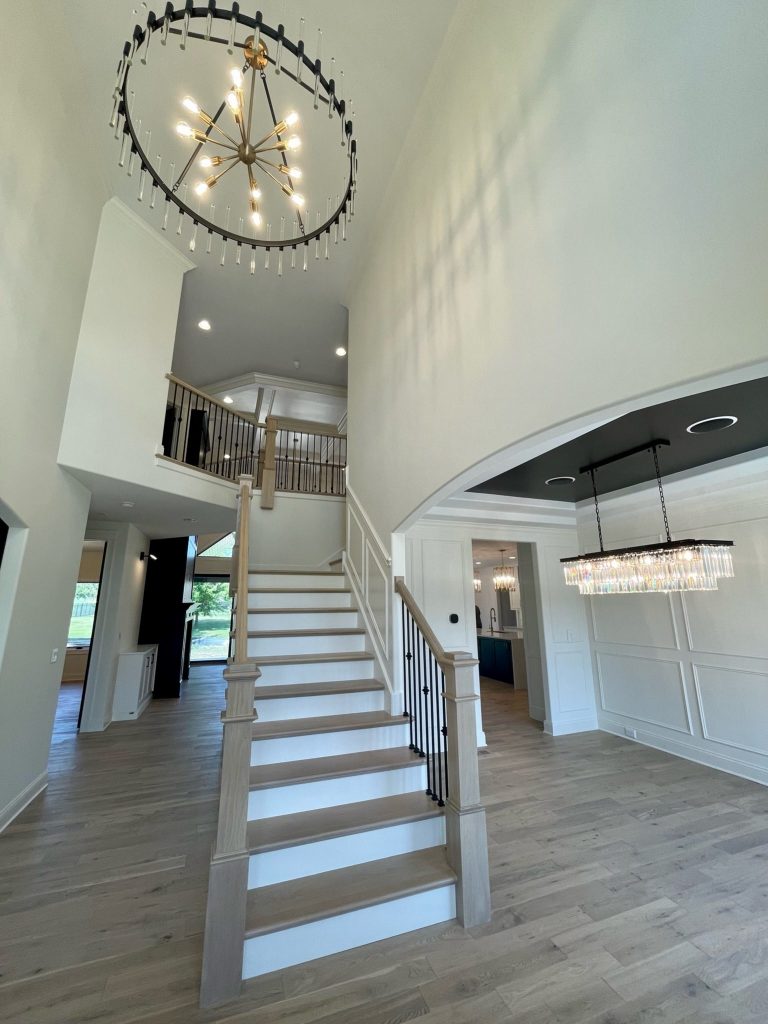 Two-story foyer with staircase and brass chandelier