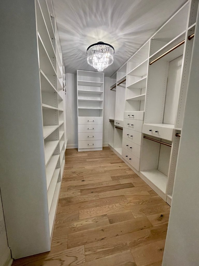 Walk-in closet with white built-ins and crystal chandelier
